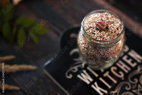 Fototapeta Naklejka Na Ścianę i Meble -  A very soft focus on a jar with hoodoo herbal folk talisman for love. Groats, rose petals and a mixture of essential oils. Esoteric, pagan, Wicca and witchcraft blurred background concept. Copy space.