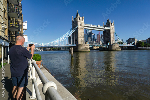 Rear view of a man photographing Tower Bridge from Butler's Wharf, London, England, UK photo