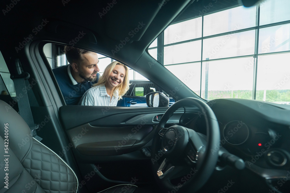 Caucasian family couple looking out the car window in a car dealership. Caucasian family couple looking out the car window in a car dealership.