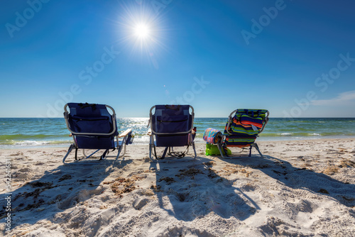 Sunny tropical beach. Three beach chairs on white sand in Miami Beach, Florida at sunrise. Summer vacation and tropical beach concept. © lucky-photo