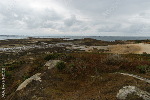 Beach with small rock islands at low tide in the background at the french coast seen from the island of Callot, Carantec, Brittany, France photo