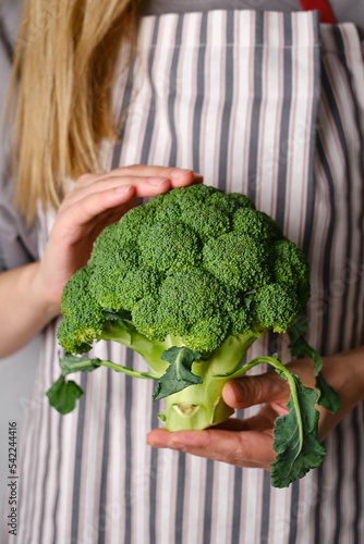 A woman holds green broccoli in her hands. Broccoli close up. Natural fresh organic vegetables. Healthy food, raw food diet. Vegetarian life. Proper nutrition. Ready to eat. Eco product