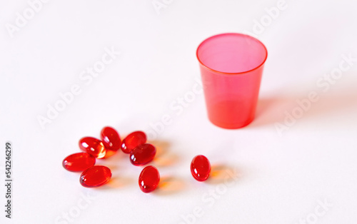 Red pill cup and red pills capsule on white background. High quality photo