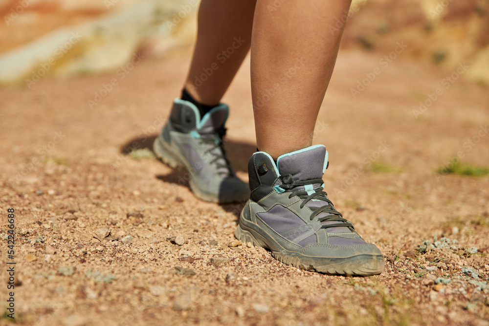 woman legs in hiking boots climbs up the sandy hill on a summer day. Tourism, travel and adventure