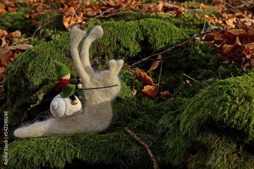 Filzwichtel reitet auf Filzschnecke durch den Wald.