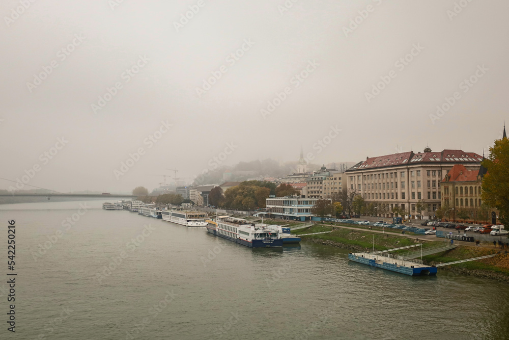 The foggy city of Bratislava. View of the city from the bridge. Parked ferries and ships.