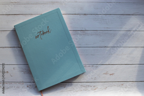 Blue paper notebook on wooden table. Notepad cover on white background. Top view, flat lay, copy space