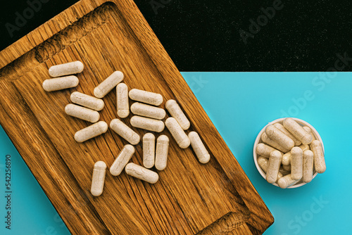 supplement capsules pills on wooden board and on cyan and chalkboard background. dietary supplements top view. immune support medical concept