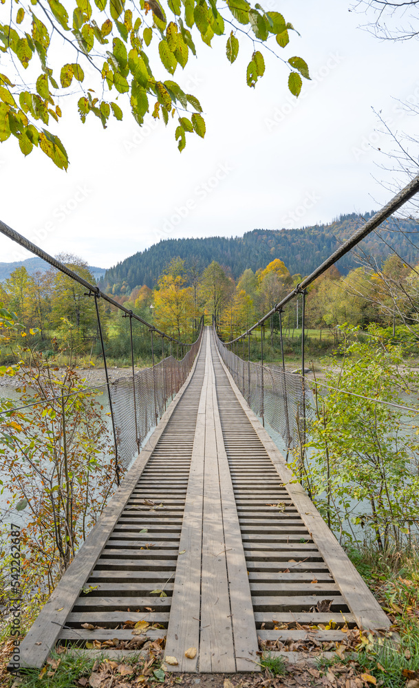 Obraz premium rope bridge over the river in autumn