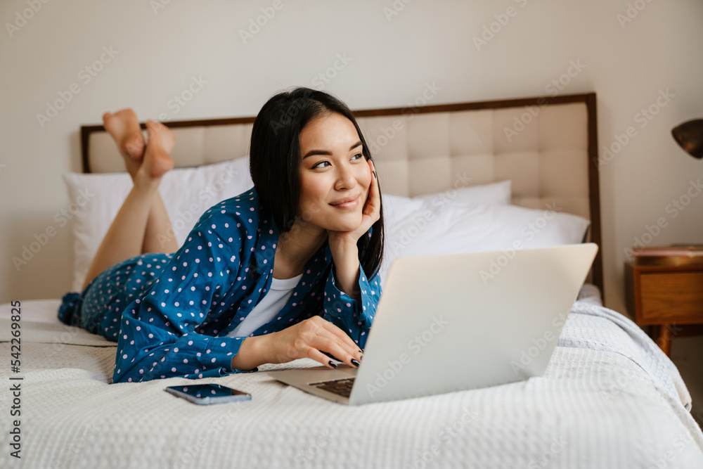 Young beautiful asian woman with laptop liying on bed Young beautiful asian woman with laptop liying on bed