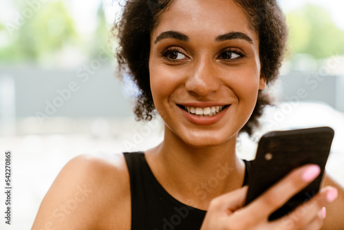 Brunette young woman using mobile phone while sitting in cafe