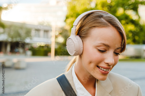 Young woman listening to music on headphones while walking on street