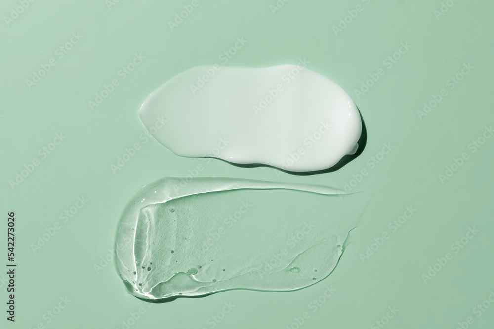cosmetic smears cream texture on green background. Beauty serum drop. Transparent and creamy skin care product sample. cosmetic smears cream texture on green background. Beauty serum drop. Transparent and creamy skin care product sample.