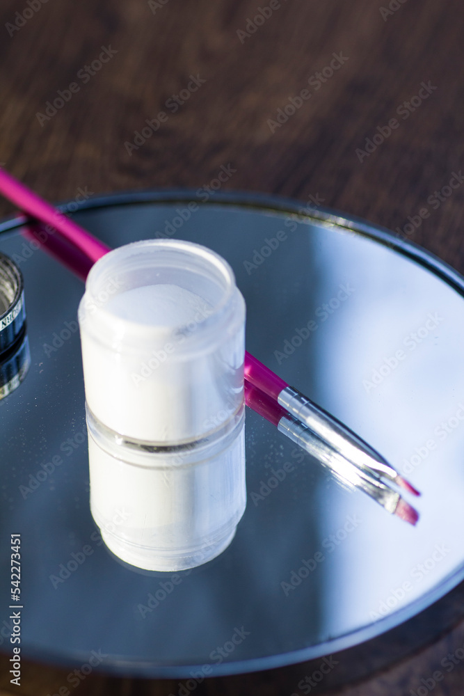 White acrylic powder to strengthen the nail plate and a brush in the reflection of the mirror White acrylic powder to strengthen the nail plate and a brush in the reflection of the mirror