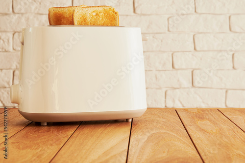 White electric toaster and ready baked bread slices on the wooden kitchen table. Cooking and homeware technologies backgrounds photo