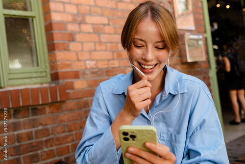 Tableau sur toile Young beautiful smiling woman in headphones with phone