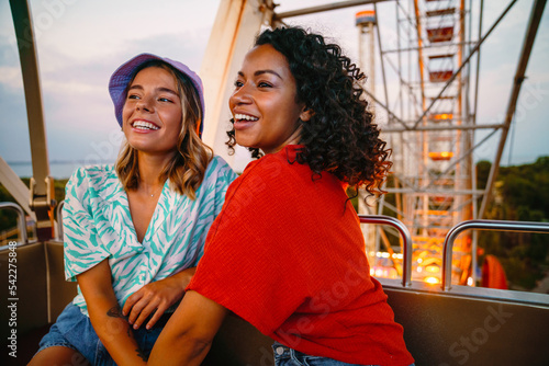 Two young beautiful attractive happy smiling girls riding Ferris wheel