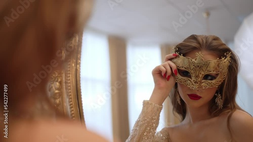 The girl puts on a mask on her face and prepares for the masquerade photo