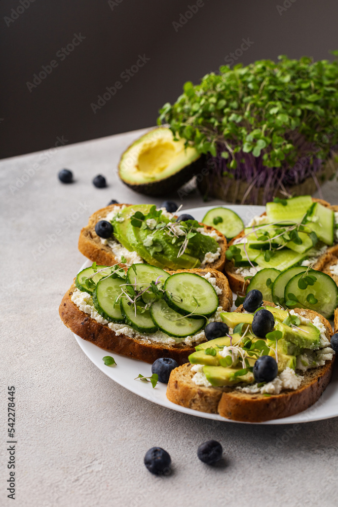 Vegetarian green sandwiches with avocado and cucumber with microgreens on a light background Vegetarian green sandwiches with avocado and cucumber with microgreens on a light background