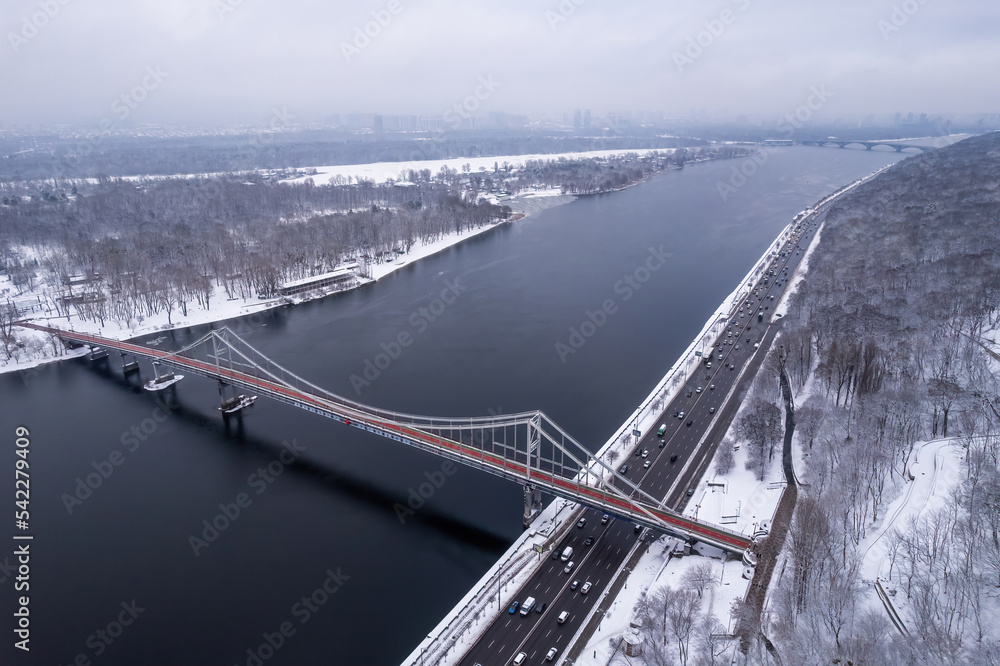 Aerial drone view. Pedestrian bridge over the frozen Dnieper River in Kiev. Cloudy frosty winter morning