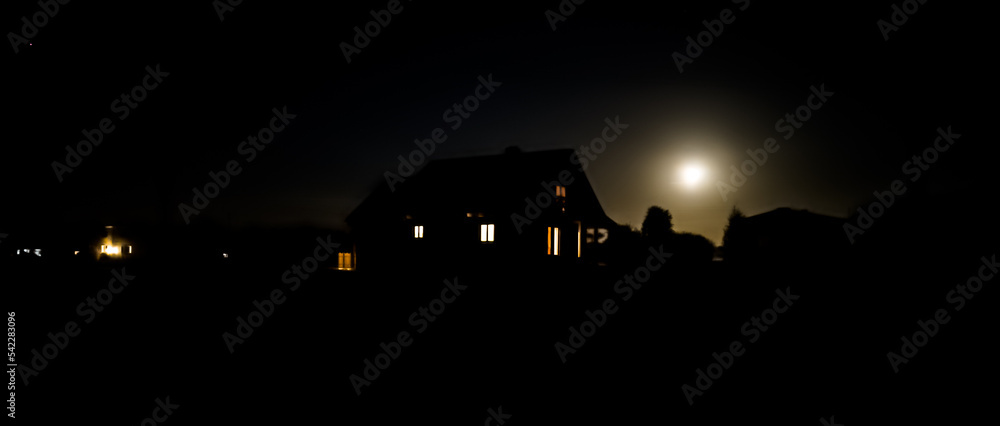 Wooden country house with light in the windows during a moonlit night