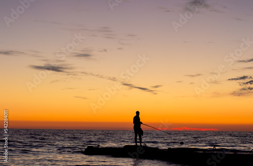 silhouette of  man on  pier by  sea against  sunset.  male fisherman holds  fishing rod,  beautiful seascape.  lonely man.