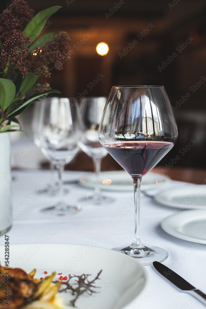 A glass of red wine on the background of the served table. Sommelier. A glass of red wine on the background of the served table. Sommelier.