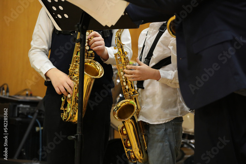 Musicians young students playing the saxophone stand in front of the notes in class in a school classroom with a teacher