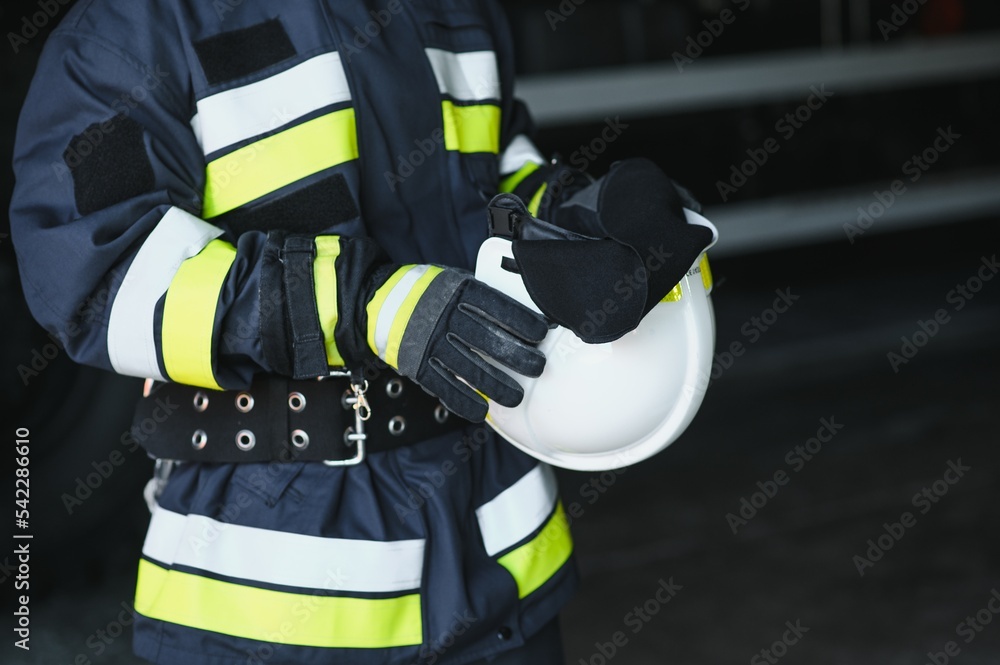 Fireman (firefighter) in action standing near a firetruck. Emergency safety. Protection, rescue from danger. Fireman (firefighter) in action standing near a firetruck. Emergency safety. Protection, rescue from danger.
