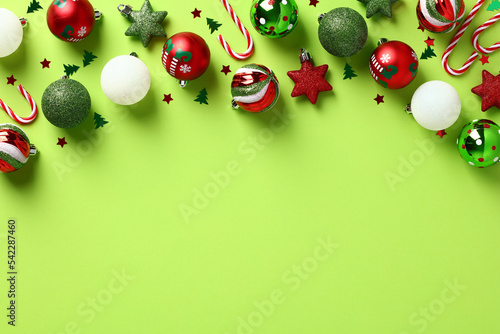 Christmas frame top border with Christmas balls, candy canes, confetti on light green background. Happy New Year greeting card template. photo