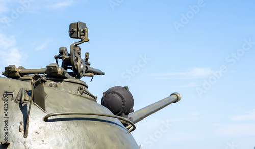 Machine gun on the turret of an armored personnel carrier. Heavy weapons of war, blue sky background. Army equipment for combat and defense. A machine gun mounted on a tank.