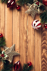 Wooden desk table background with Christmas decorations and fir tree branches on corners of frame. Christmas vertical banner design, poster template. Flat lay, top view, copy space.