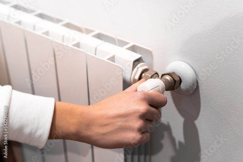 Girl feeling cold with home heating trouble. Energy crisis concept. Radiator thermostat showing cold temperature. Electricity and gas bill goes up. Radiators turns off. Heating problem. Degress