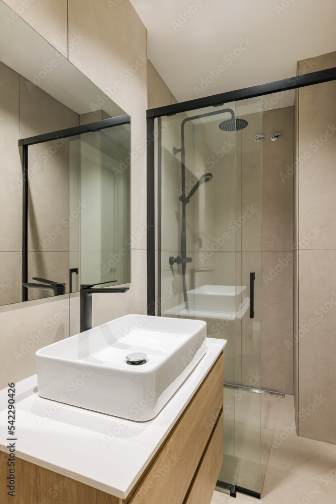 Interior of modern style bathroom in refurbished apartment. Shower zone and sink with black faucet and mirror. Interior of modern style bathroom in refurbished apartment. Shower zone and sink with black faucet and mirror.
