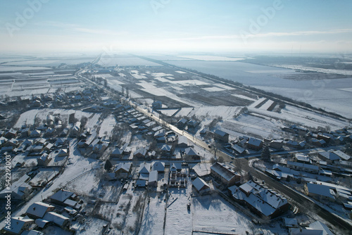 Top view of the highway and the parallel railroad. Snow-covered fields and houses.