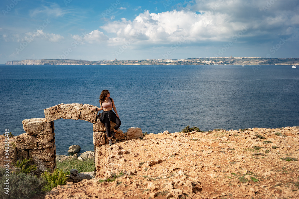 young girl exploring the door to the sea. Ghar Tuta, Mellieha, Malta