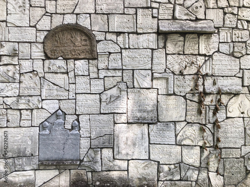 Ruined jewish tombstones matzevah on a wall in the jewish cemetery Remah Synagogue in Kazimierz district of Krakow, Poland photo