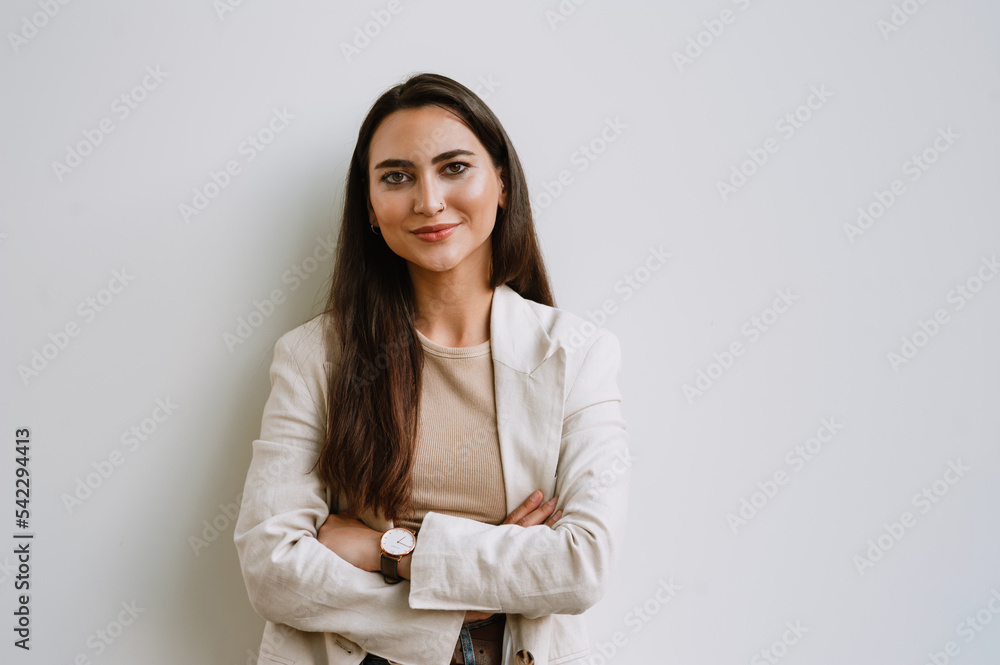Young indian woman smiling and looking at camera while standing by wall Young indian woman smiling and looking at camera while standing by wall