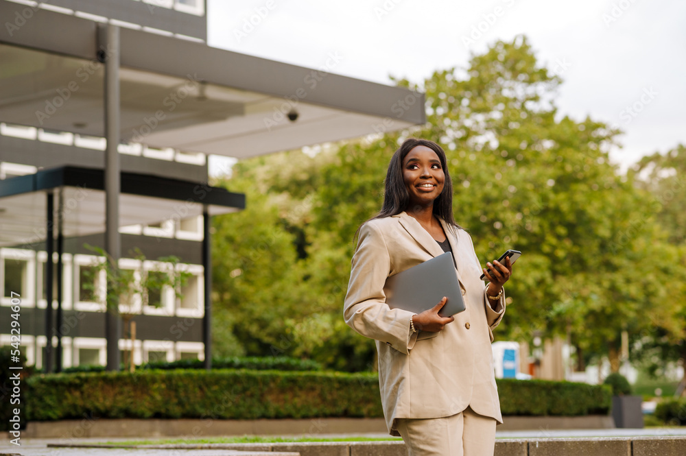 Young black businesswoman using cellphone while walking outdoors Young black businesswoman using cellphone while walking outdoors