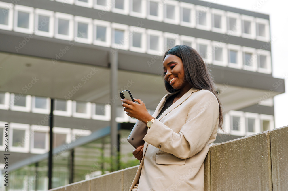 Young black businesswoman using cellphone while walking outdoors Young black businesswoman using cellphone while walking outdoors