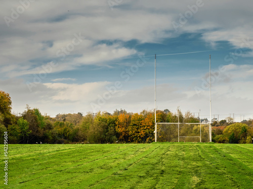 Training pitch for Irish National sport camogie, hurling, rugby and Gaelic football with tall goal posts and freshly cut grass. Nobody. Cloudy sky. Popular activity.