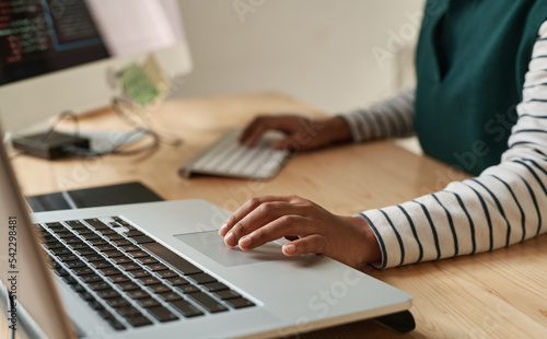 Hand of young black woman over laptop touchpad during network or creation of new website while sitting by workplace in office photo