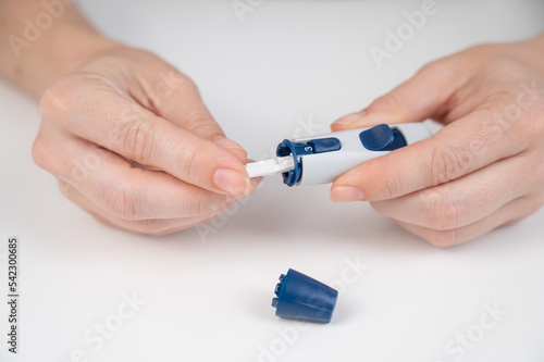 Caucasian woman inserts a needle into a lancet pen. 