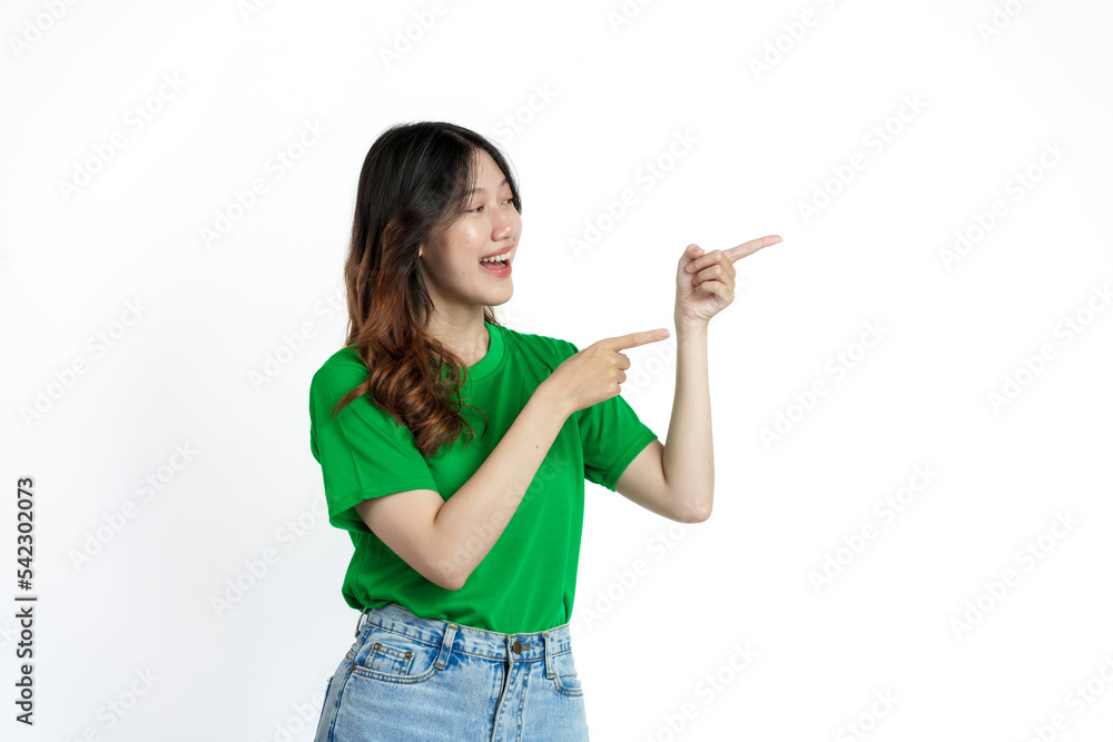 Beautiful confident Asian woman in green empty t-shirt isolated on white background. Point your finger to copy space to introduce products or services Beautiful confident Asian woman in green empty t-shirt isolated on white background. Point your finger to copy space to introduce products or services