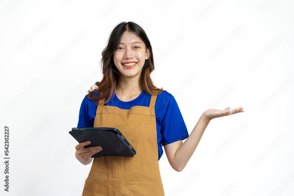 Using tablet, Cheerful young pretty asian woman blue t-shirt and apron coffee owner isolated on white background. checking order online Using tablet, Cheerful young pretty asian woman blue t-shirt and apron coffee owner isolated on white background. checking order online