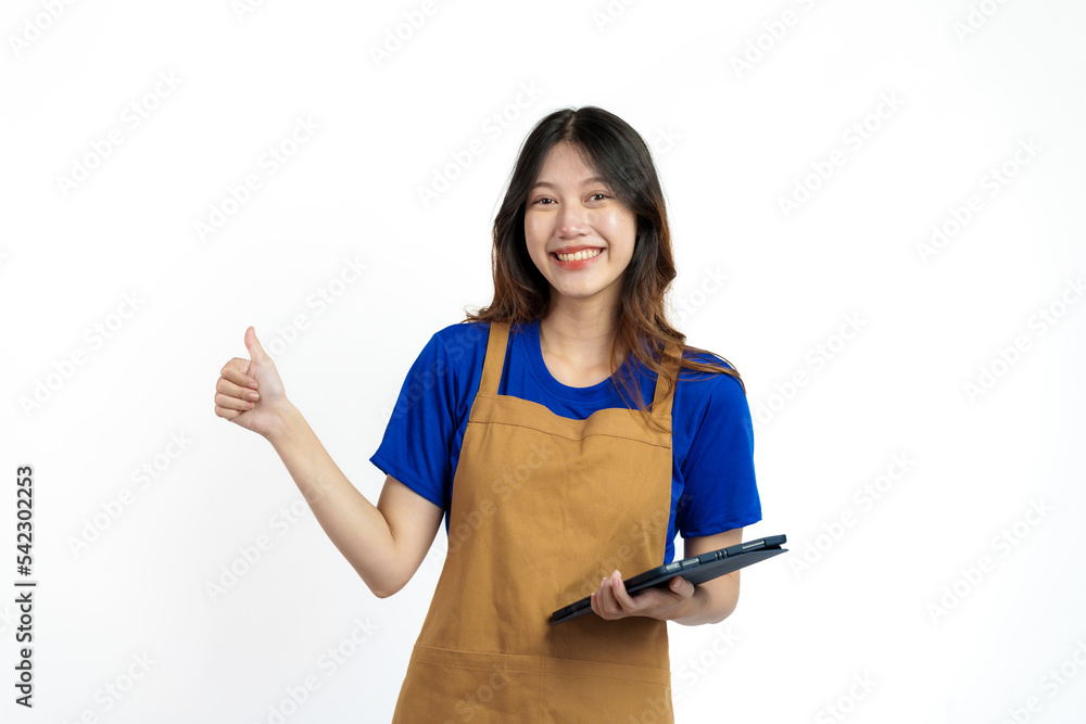 Using tablet, Cheerful young pretty asian woman blue t-shirt and apron coffee owner isolated on white background. checking order online Using tablet, Cheerful young pretty asian woman blue t-shirt and apron coffee owner isolated on white background. checking order online