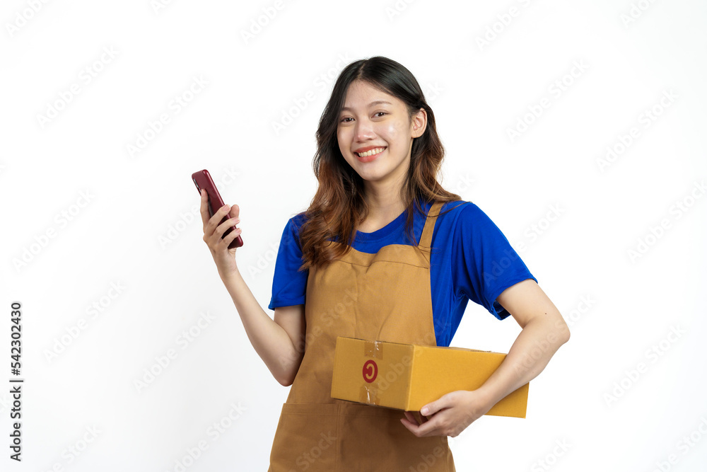 Young pretty asian woman with apron holding packages box of product for delivery sme entrepreneur owner isolated on white background. Using mobile