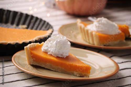 Fresh homemade pumpkin pie with whipped cream on table