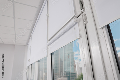 Plastic windows with white roller blinds indoors