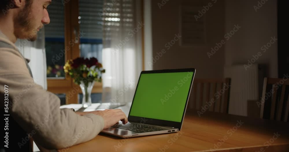 someone is typing on the laptop with a green screen in the living room, with light from outside (film set) someone is typing on the laptop with a green screen in the living room, with light from outside (film set)